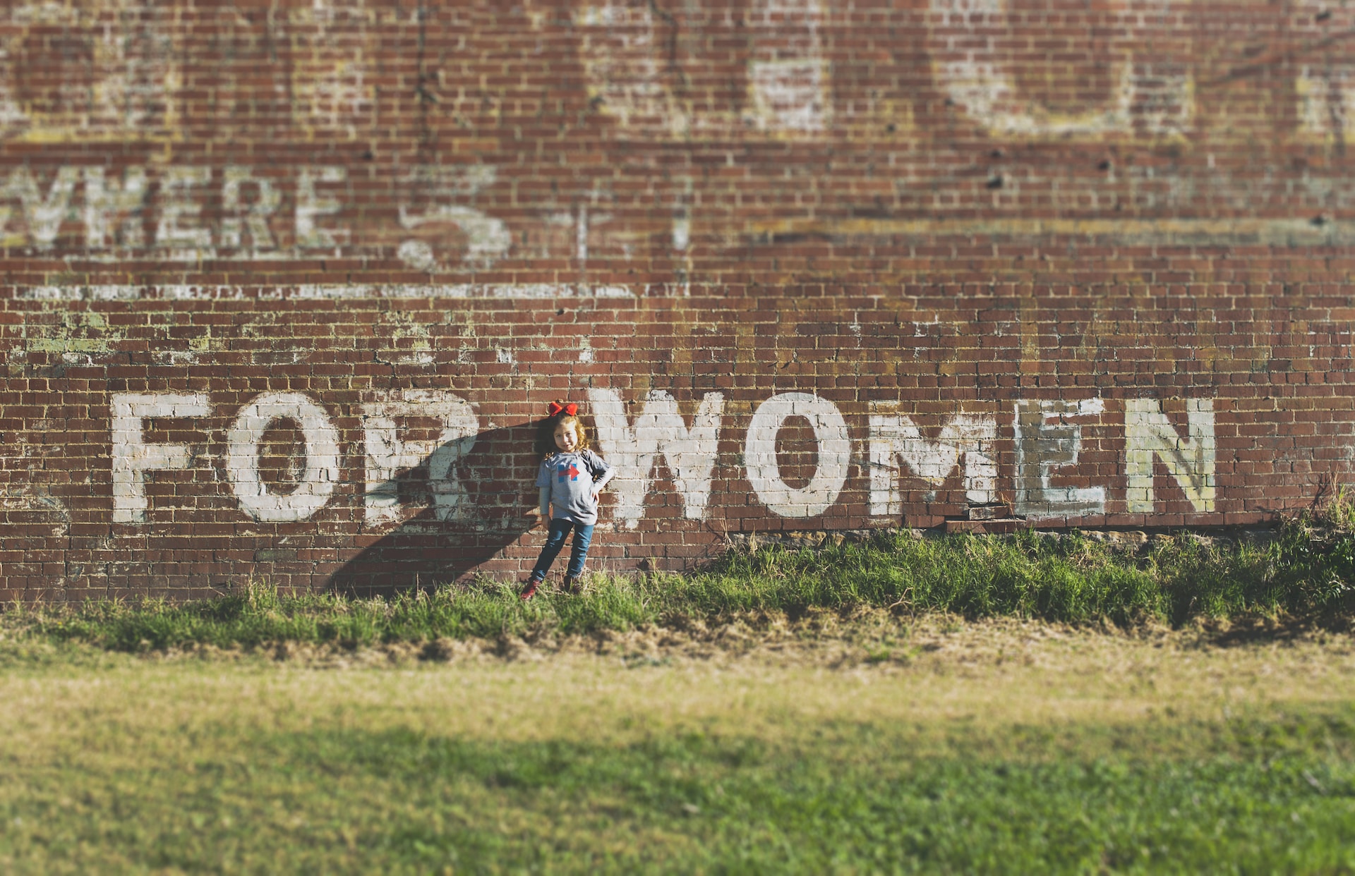 Sassy young girl standing in front of FOR WOMEN painted on brick wall