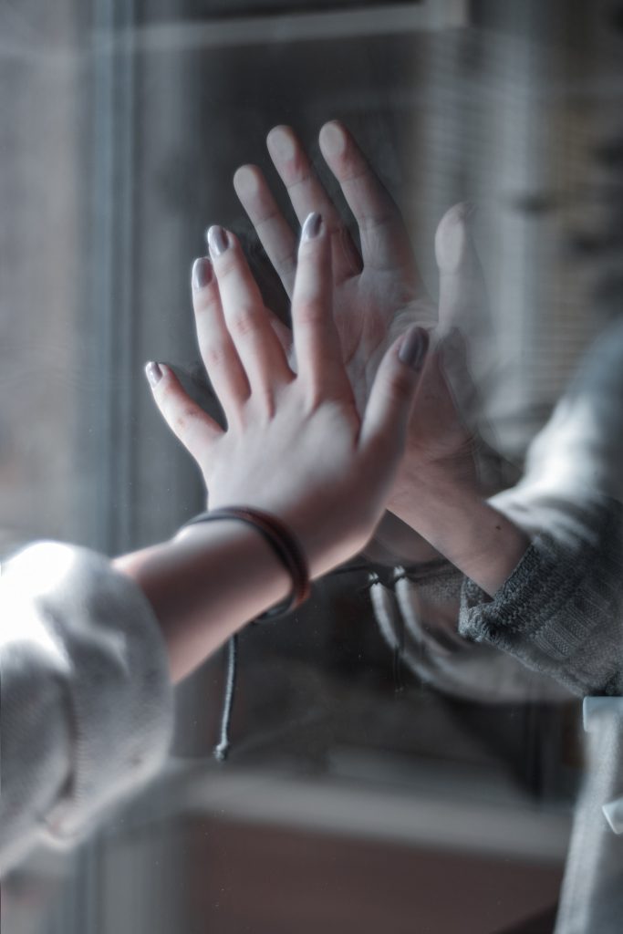 Hands meeting through glass